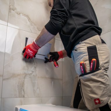 a man in a black shirt and red gloves working on a toilet