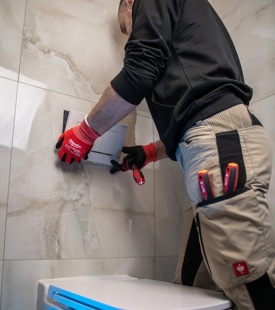 a man in a black shirt and red gloves working on a toilet