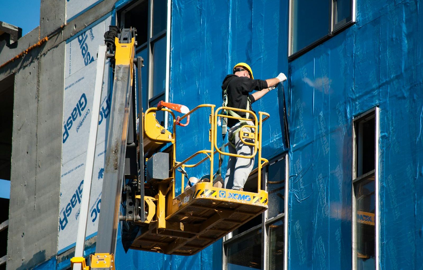 Worker Insulating a Building from the Skylift Basket