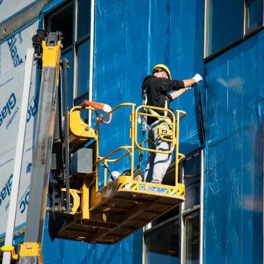 Worker Insulating a Building from the Skylift Basket