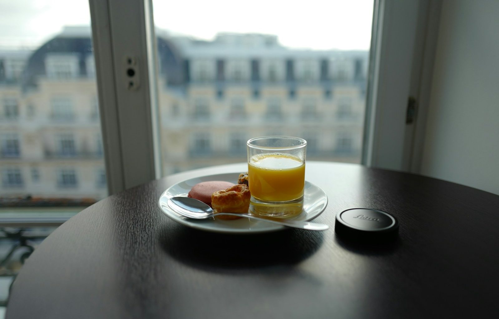 cup filled with yellow liquid beside bread on plate