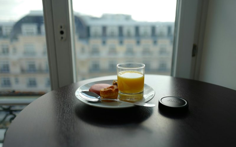 cup filled with yellow liquid beside bread on plate