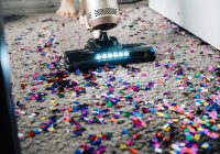 a person using a vacuum to clean a carpet