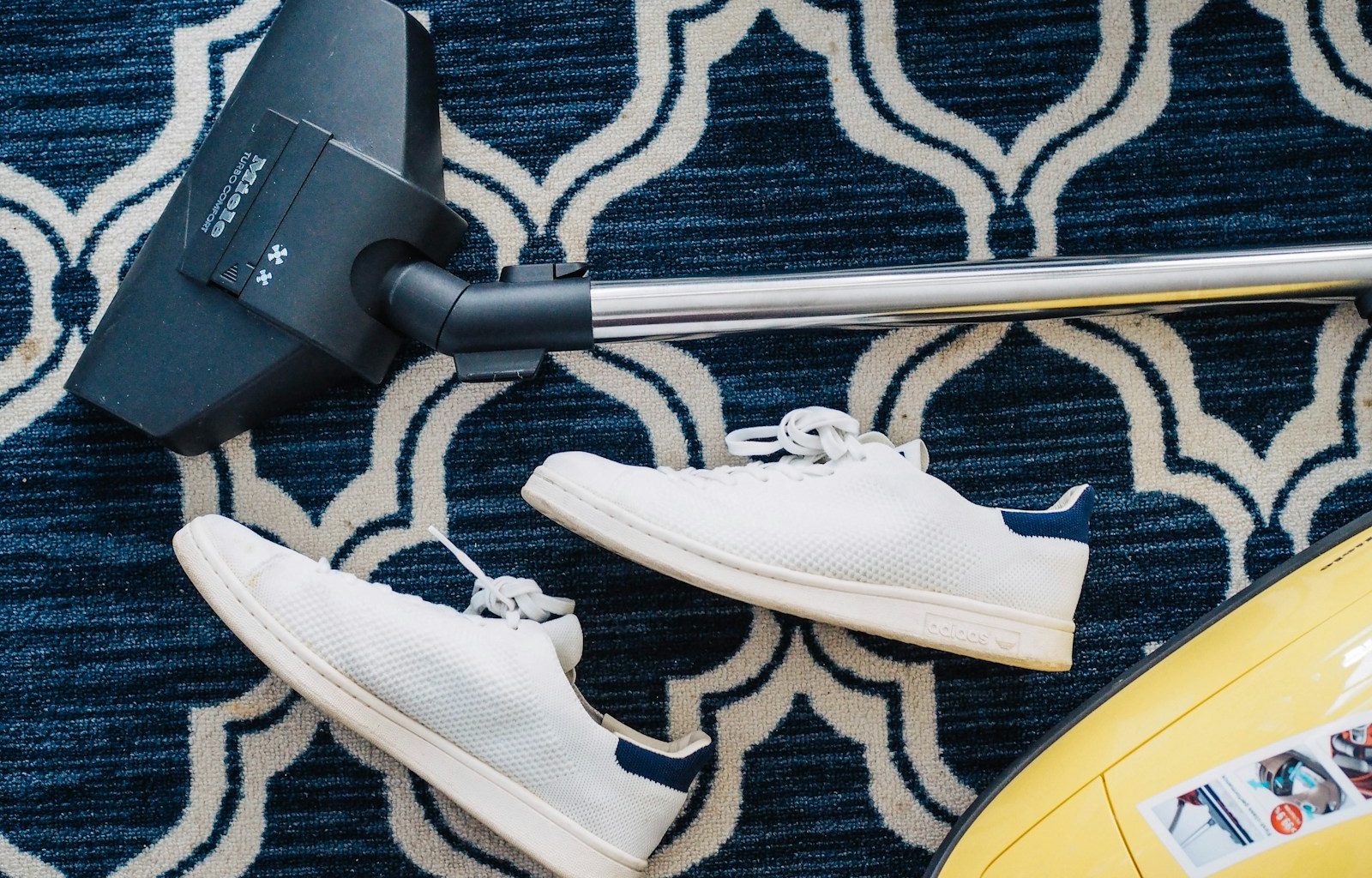 pair of white sneakers beside vacuum cleaner